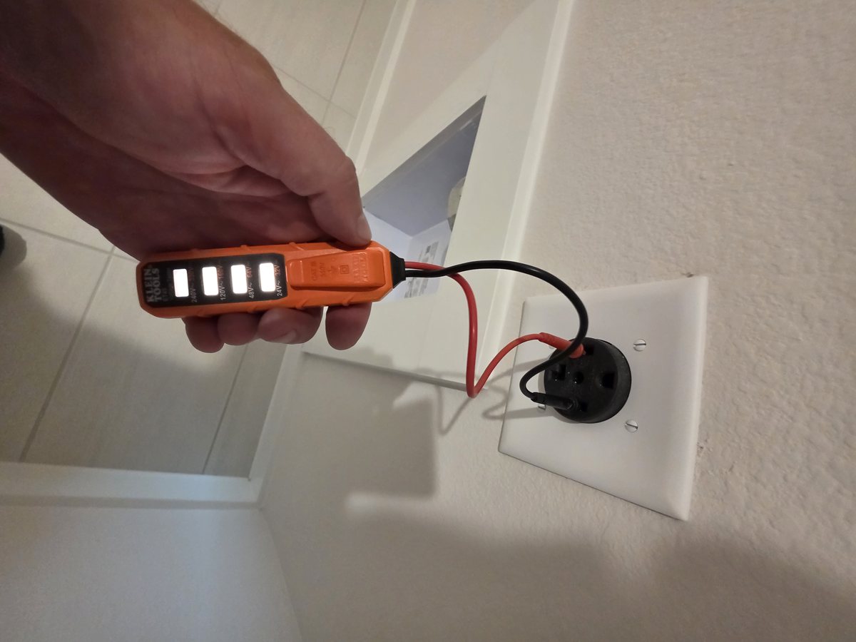 Voltage tester checking a 240-volt four-prong dryer receptacle