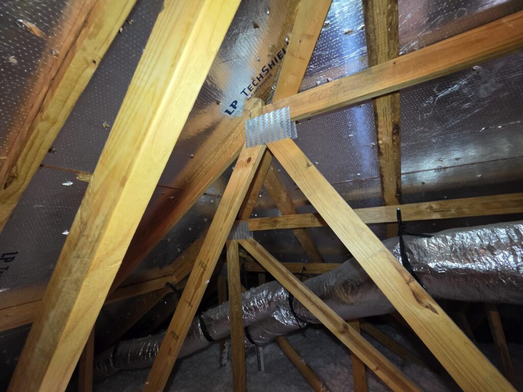 Armaduras del techo en el ático y ductos de HVAC con aislamiento
