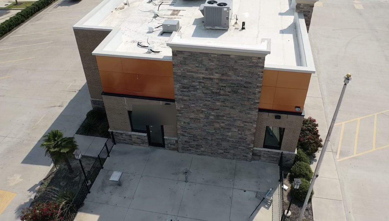 Vista con dron de un edificio comercial pequeño con techo plano y HVAC en el techo