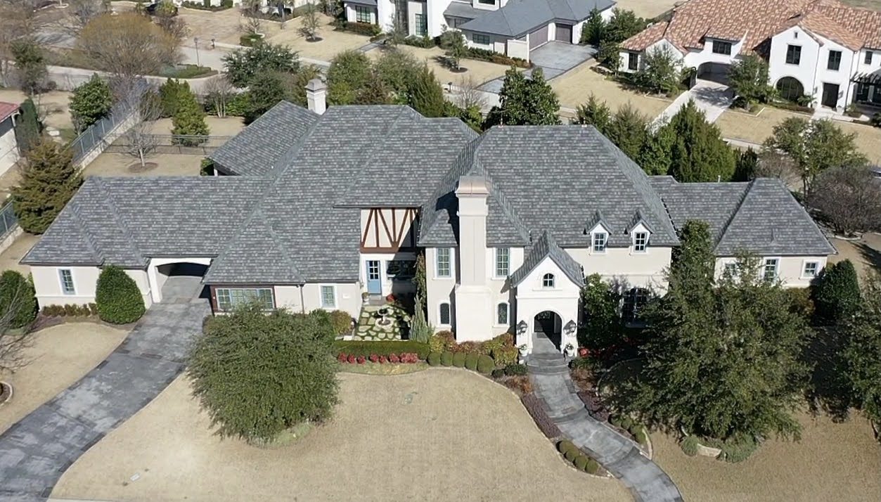 Vista con dron de una casa grande con entrada circular y jardines maduros