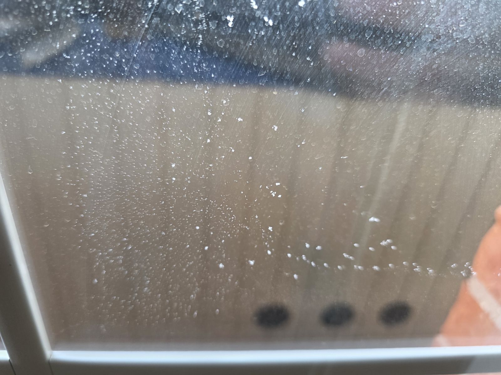 Acercamiento de gotas de condensación atrapadas entre los vidrios de una ventana con el sello dañado