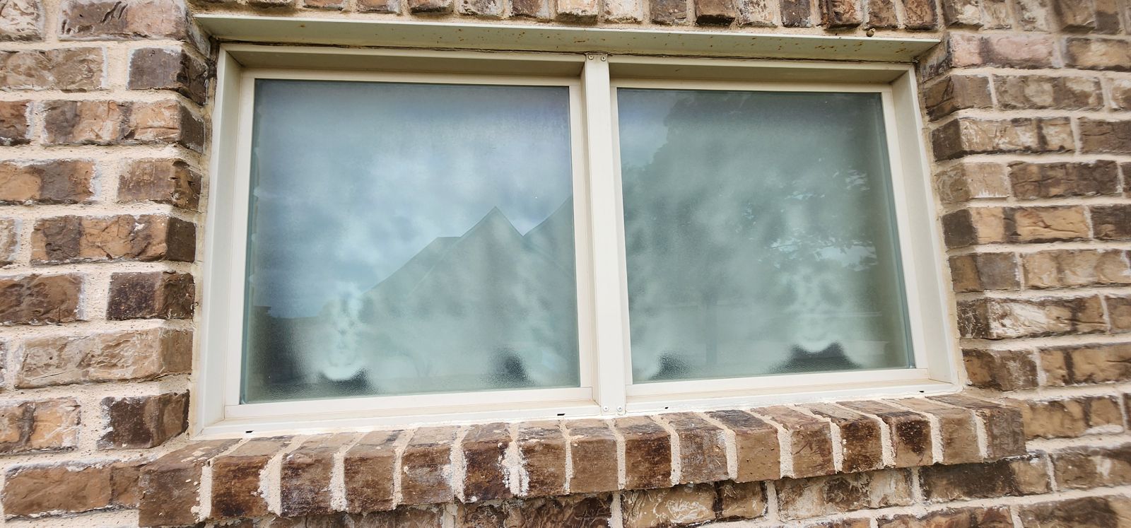 Vista exterior de una ventana doble con empañamiento borroso entre los vidrios