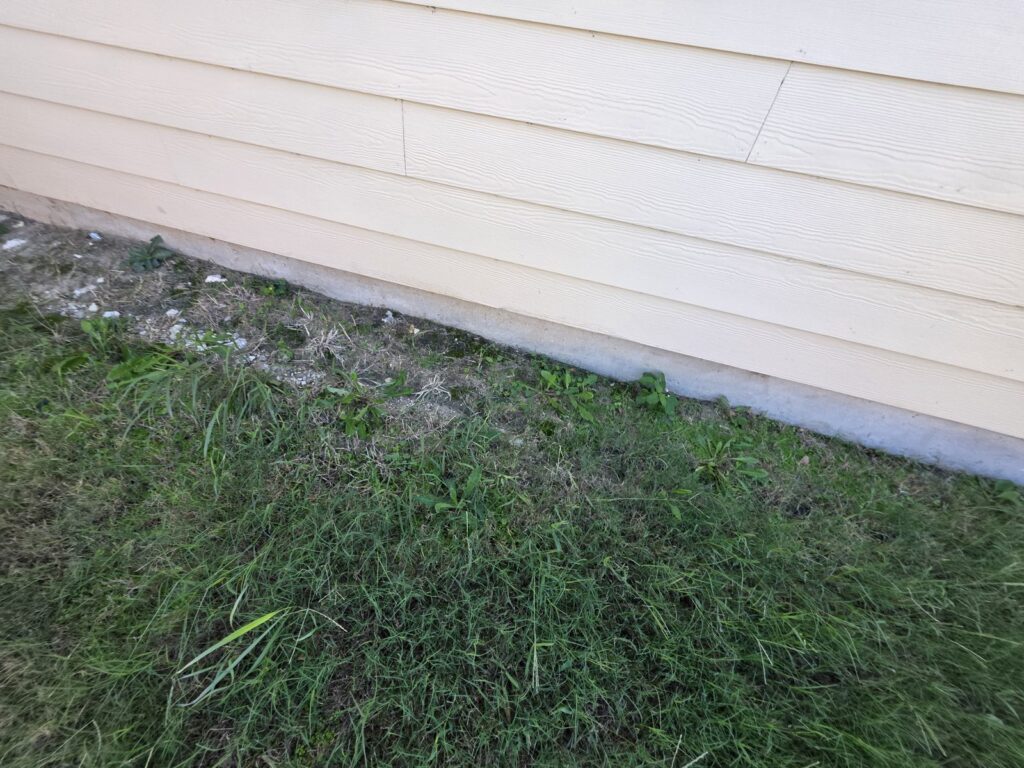 Orilla expuesta de la losa del cimiento debajo del siding