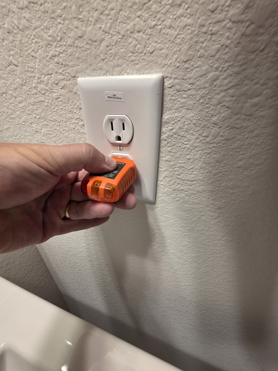 Inspector testing GFCI protection at a bathroom receptacle