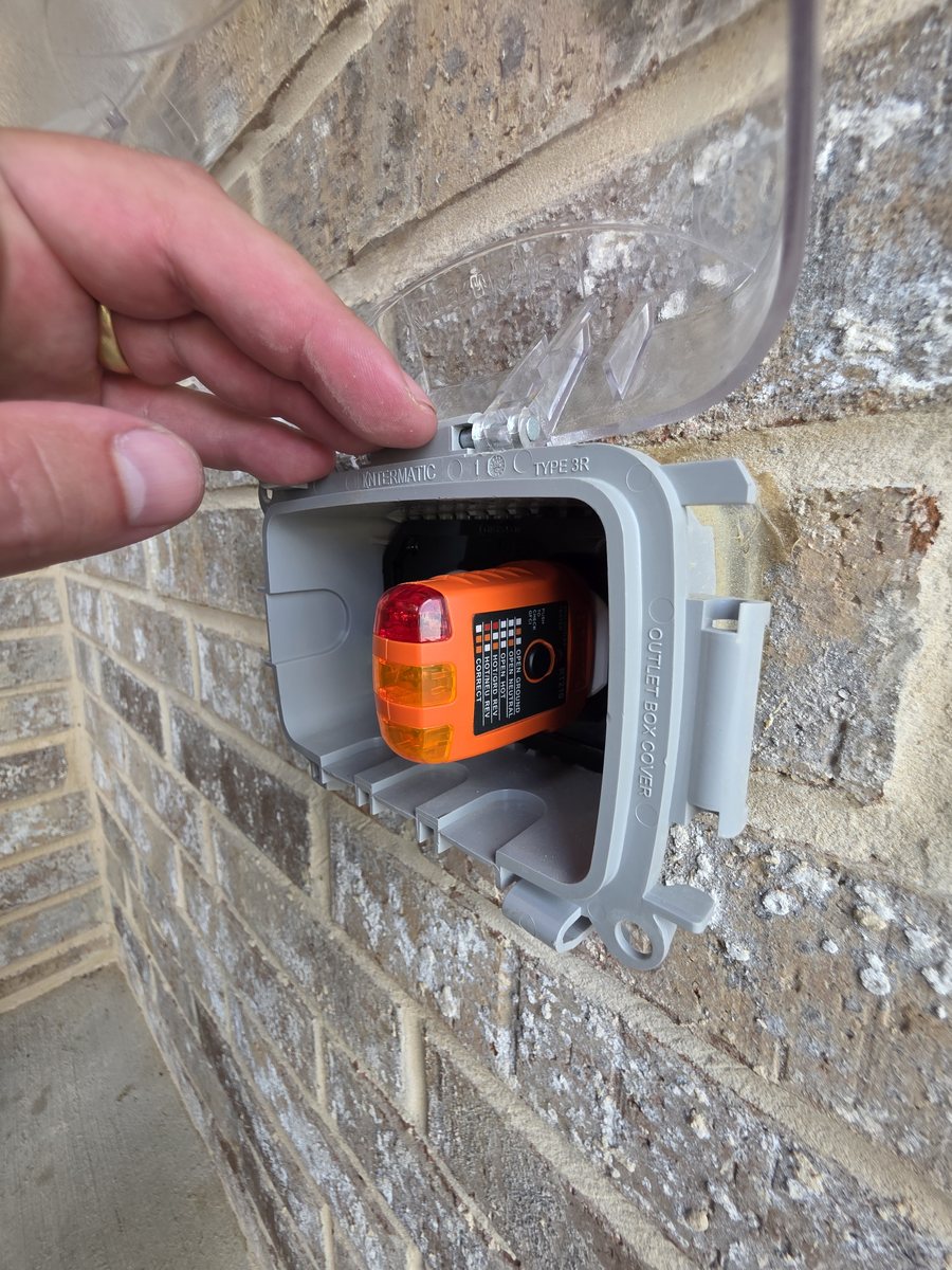 GFCI tester in an exterior receptacle under a weatherproof in-use cover on a brick wall