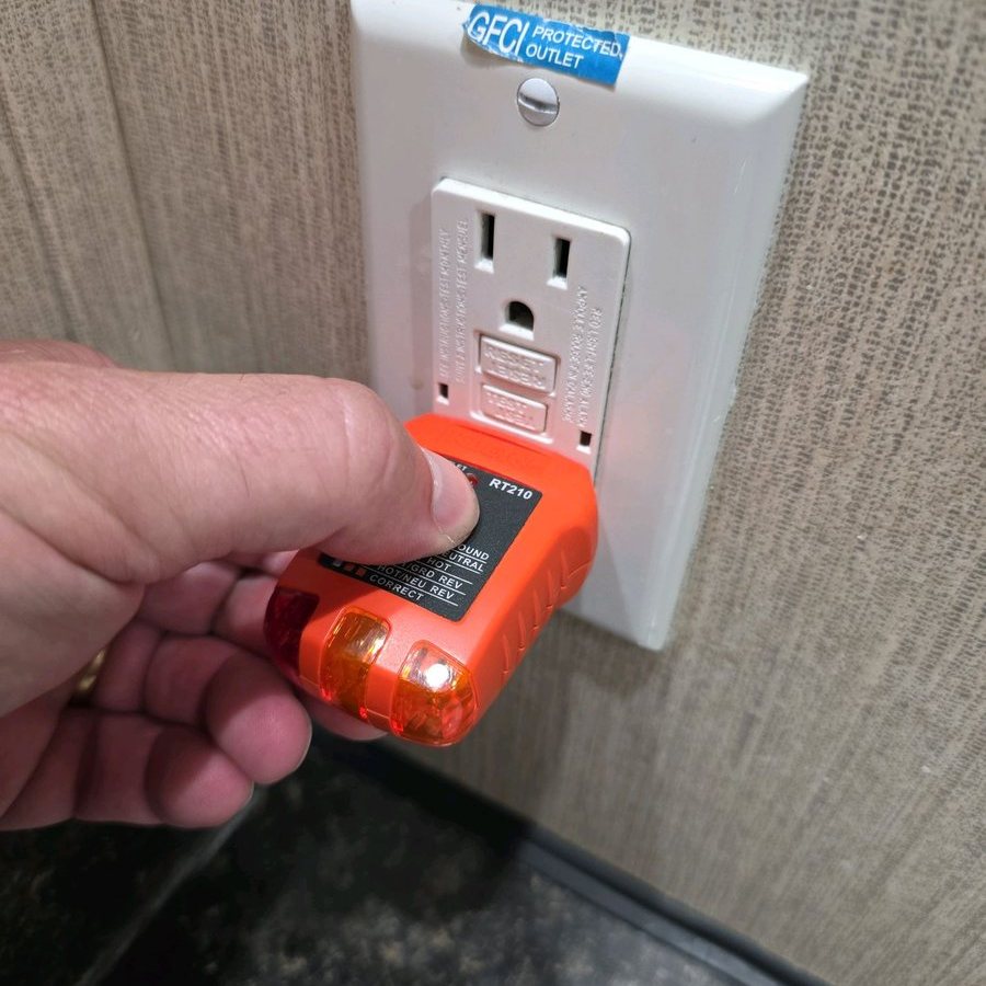 Inspector pressing the test button on a GFCI tester plugged into a kitchen receptacle labeled GFCI Protected Outlet
