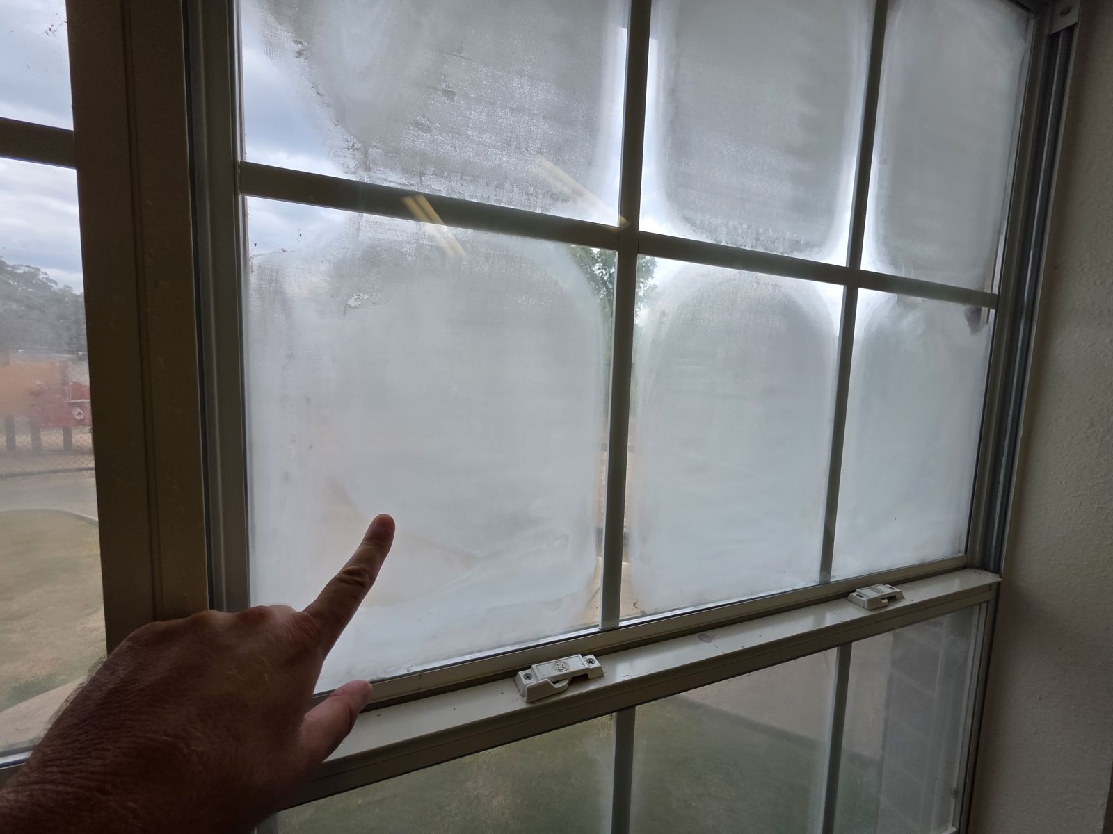 Inspector señalando el empañamiento dentro de una ventana de doble vidrio con cuadrícula