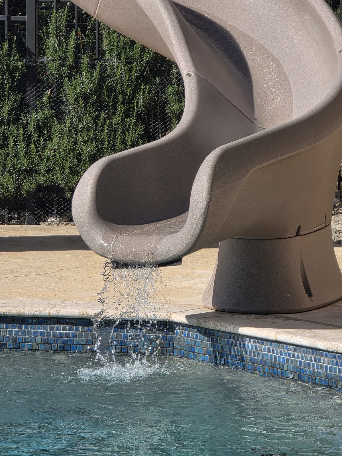Resbaladilla de alberca con agua corriendo sobre la línea de azulejo