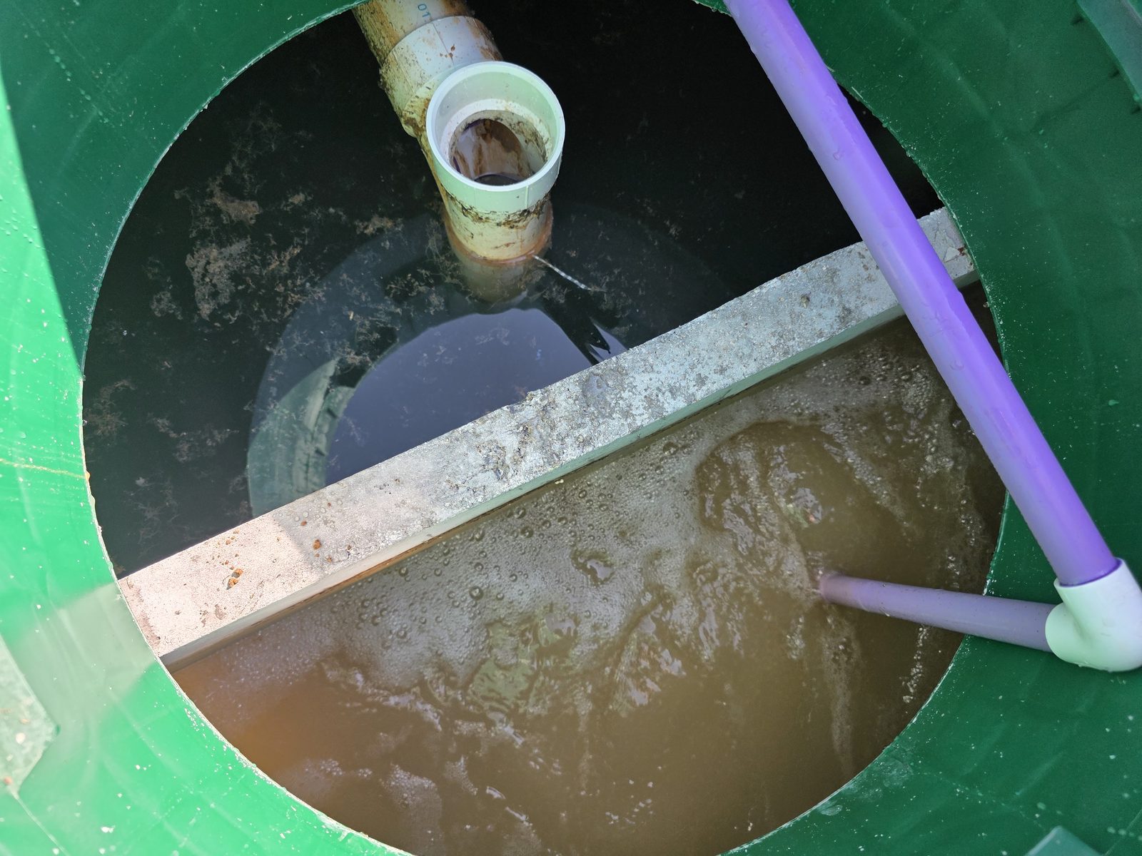 Compartimento del tanque séptico con nivel de líquido y tubo de entrada