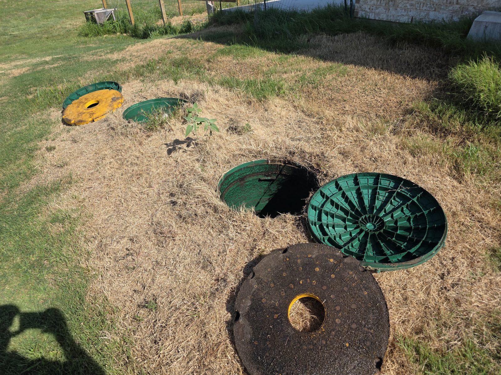 Registros verdes del tanque séptico sin tapa en un pasto seco
