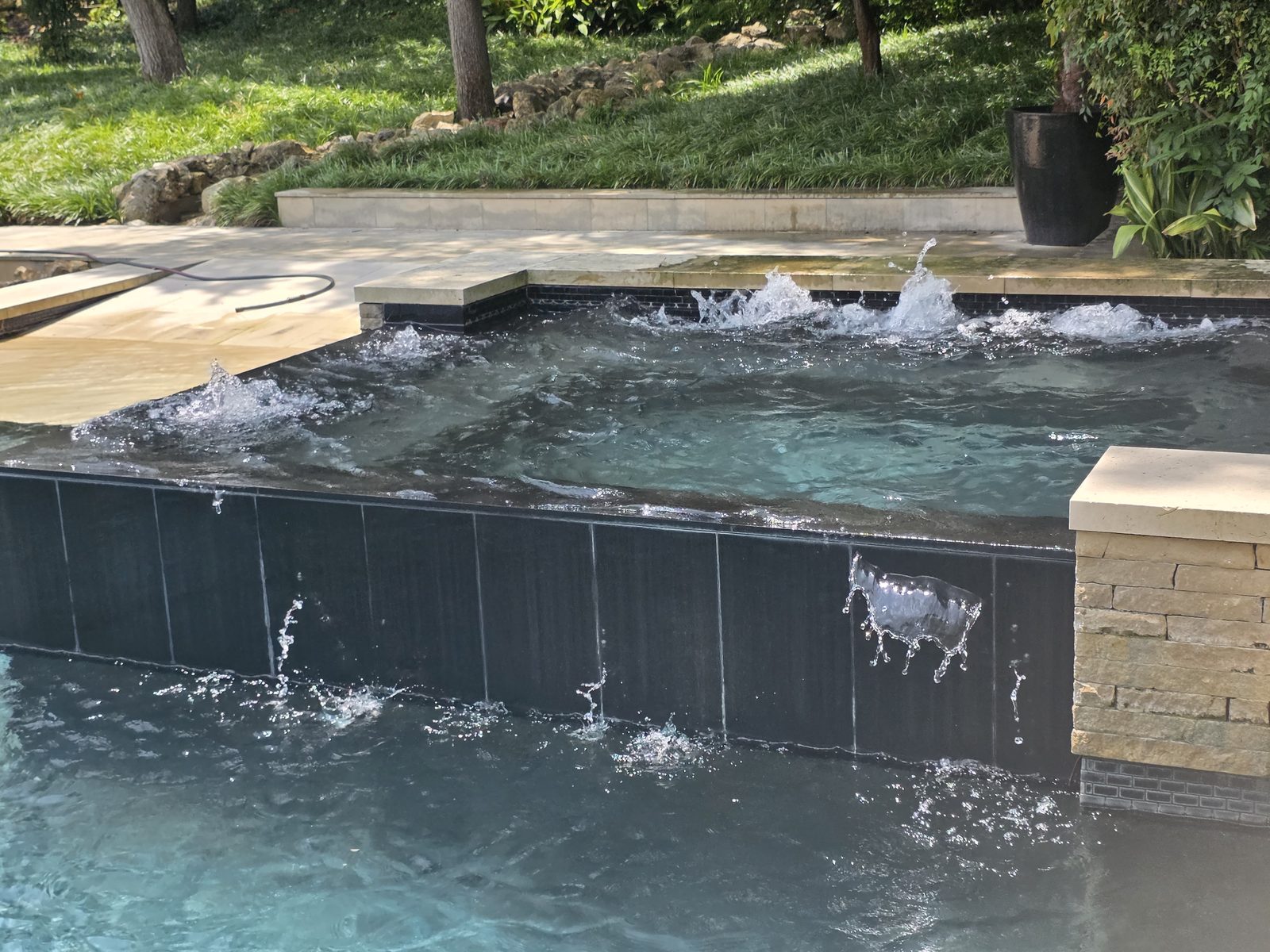 Cascada del jacuzzi sobre una pared de azulejo hacia la alberca