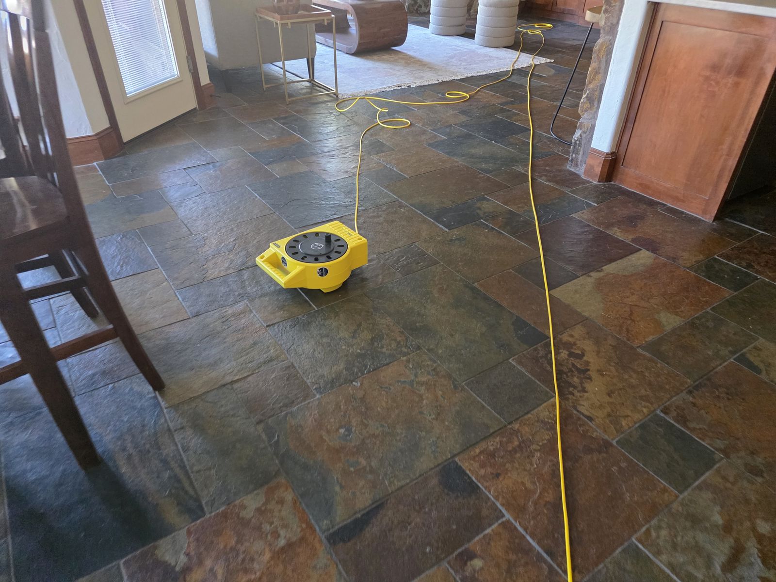 ZipLevel reference base on slate tile with the yellow hose running across the living and kitchen area