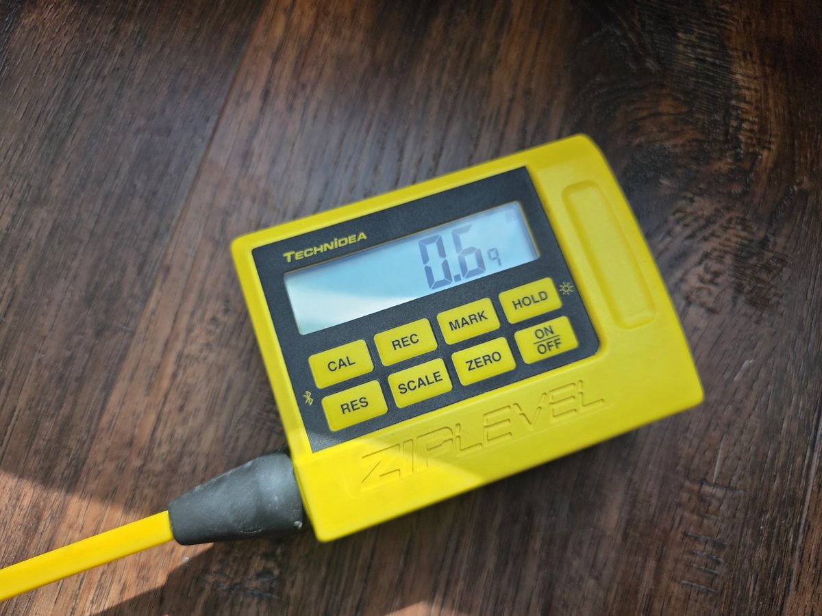 ZIPLEVEL handheld readout showing a floor elevation reading on a wood floor